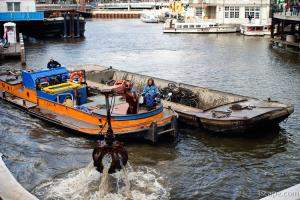 Garbage picker and barge grabbing bikes from the canal