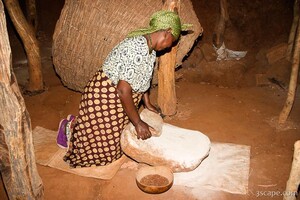 Iraqw woman demonstrating grain grinding techniques