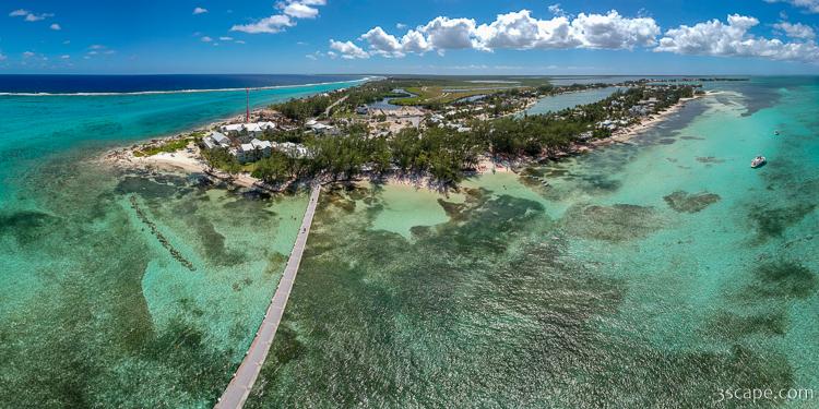 Aerial panoramic view of Rum Point, a sandy peninsula on Grand Cayman's north side, with a long pier extending into shallow turquoise water