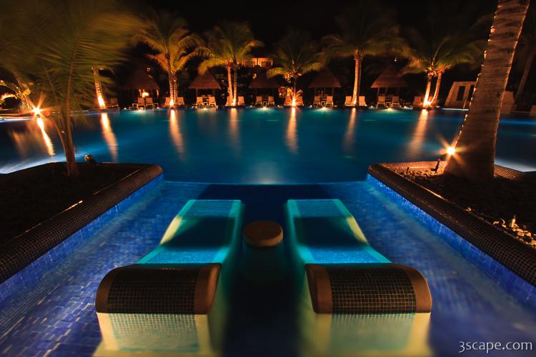 Night shot of the adult pool with sunken loungers